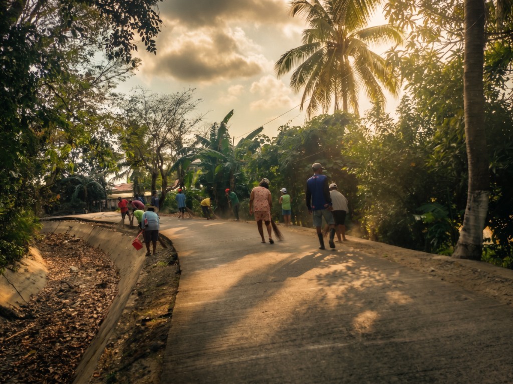 Residents sweeping the sitio road and clearing drainage during a Kalinisan Day cleanup